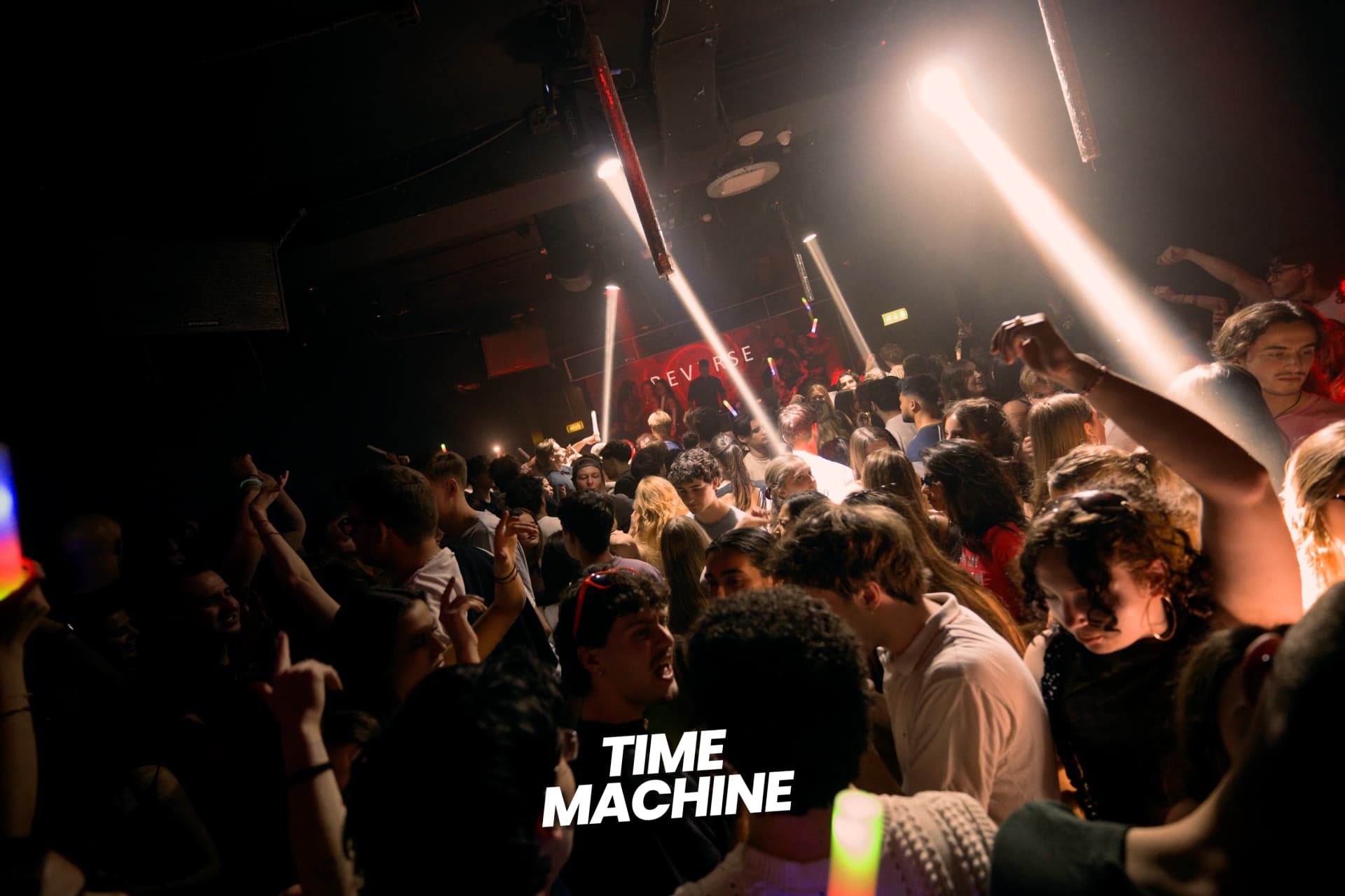 Crowd at a Time Machine event under red light and spotlights