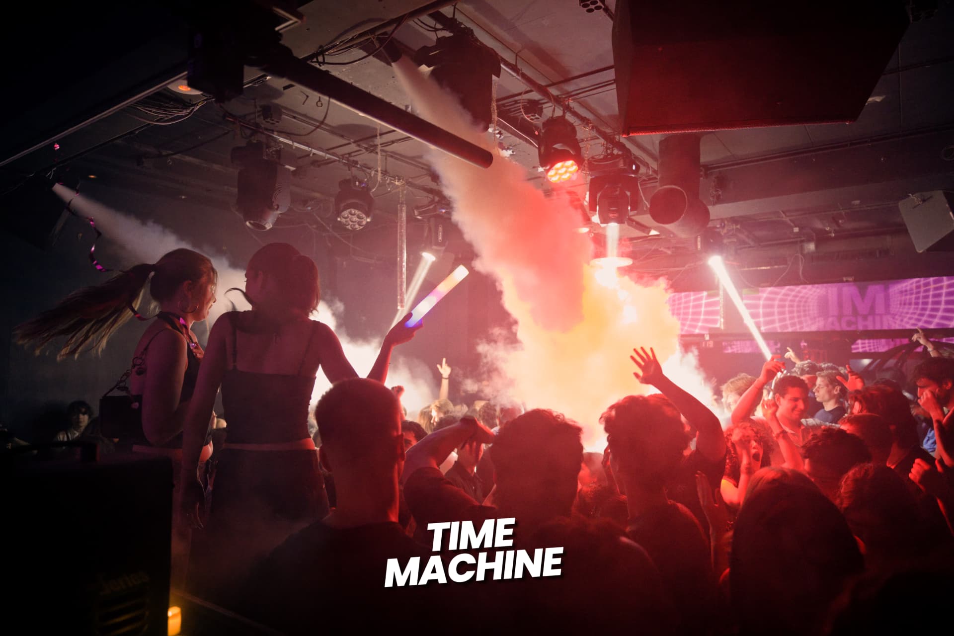 Crowd under red light and smoke jets at a Time Machine event